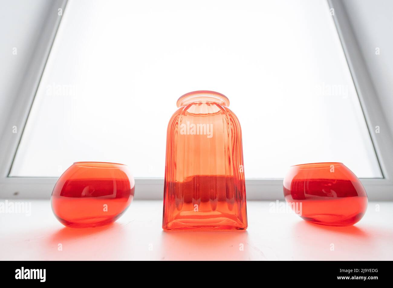 Three empty glass red vases on the windowsill. Stock Photo