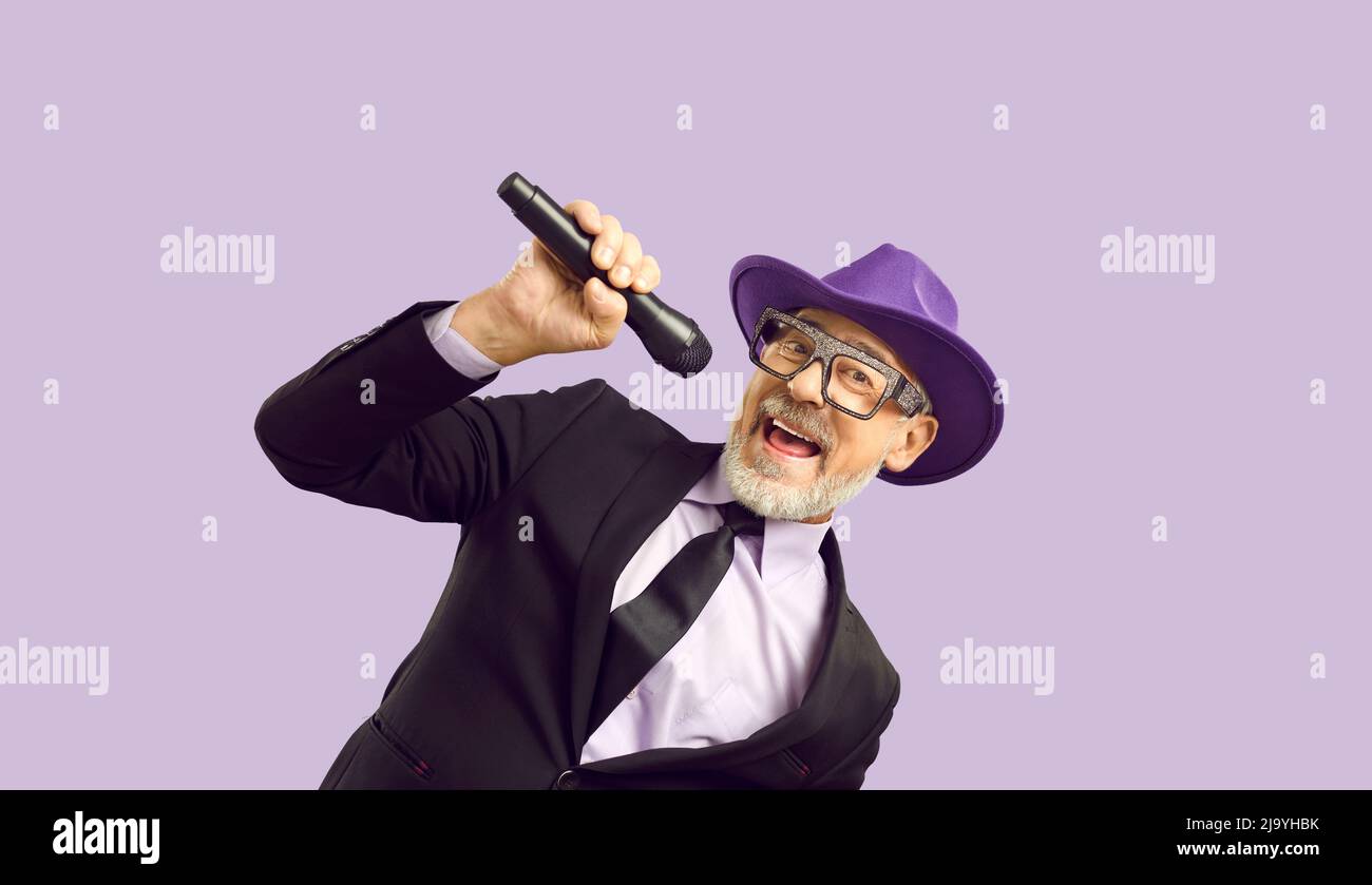 Talented caucasian senior man, mc showman singing hit isolated over purple background Stock Photo