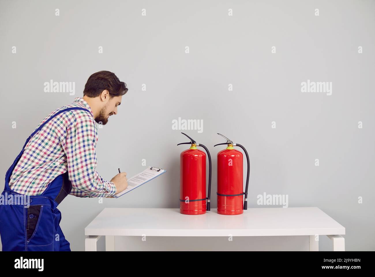 Fire safety inspector taking notes while checking fire extinguishers in