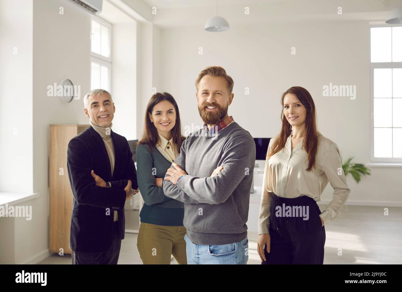 Smiling coworkers stand looking at camera creating team shots in office together. Stock Photo