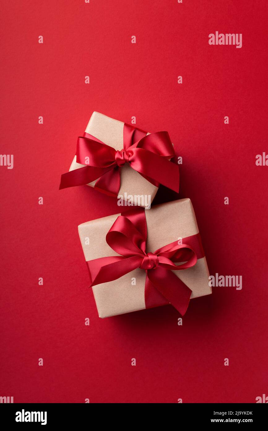 Two gift boxes tied red ribbons on red background. Stock Photo