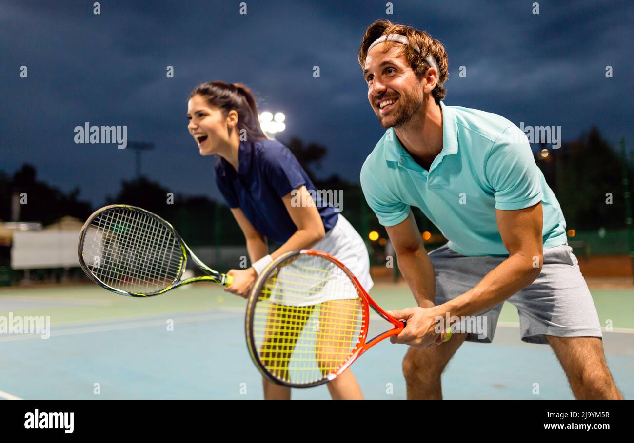 Beautiful young people are playing tennis as a team on tennis court outdoors. People sport concept Stock Photo