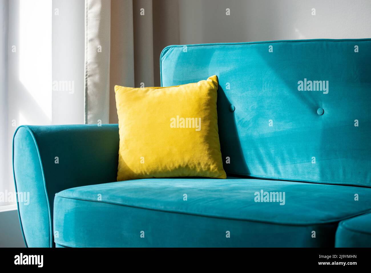 https://c8.alamy.com/comp/2J9YMHN/bright-yellow-pillow-on-blue-turquoise-sofa-or-couch-interior-of-the-comfortable-residential-room-2J9YMHN.jpg