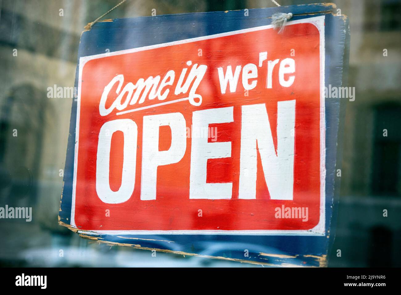 Wooden sign board with text we are open next to glass door in London Stock Photo