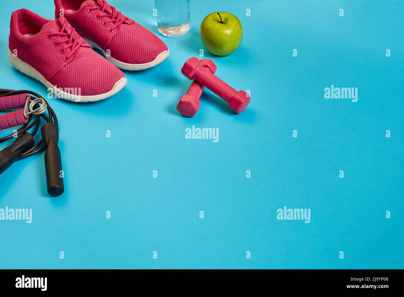 Flat lay of dumbbell, bottle of water, jump rope and sneaker, sport equipments, fitness items