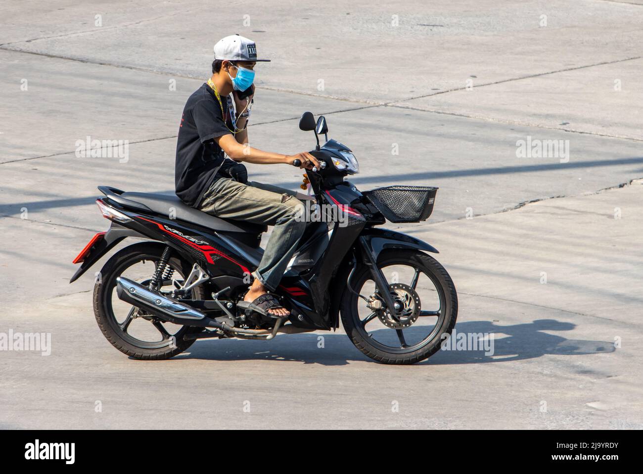 SAMUT PRAKAN, THAILAND, MARCH 06 2022, A man riding a motorcycle and calling from a cell phone Stock Photo