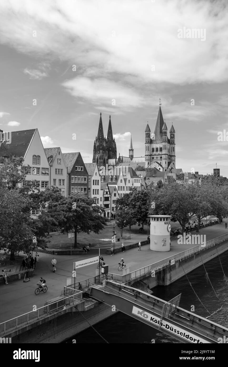 Cologne, Germany - May 17, 2022 : Panoramic view of the cathedral Saint Martin, the Dom and people walking next to the river Rhine of Cologne in black and white Stock Photo