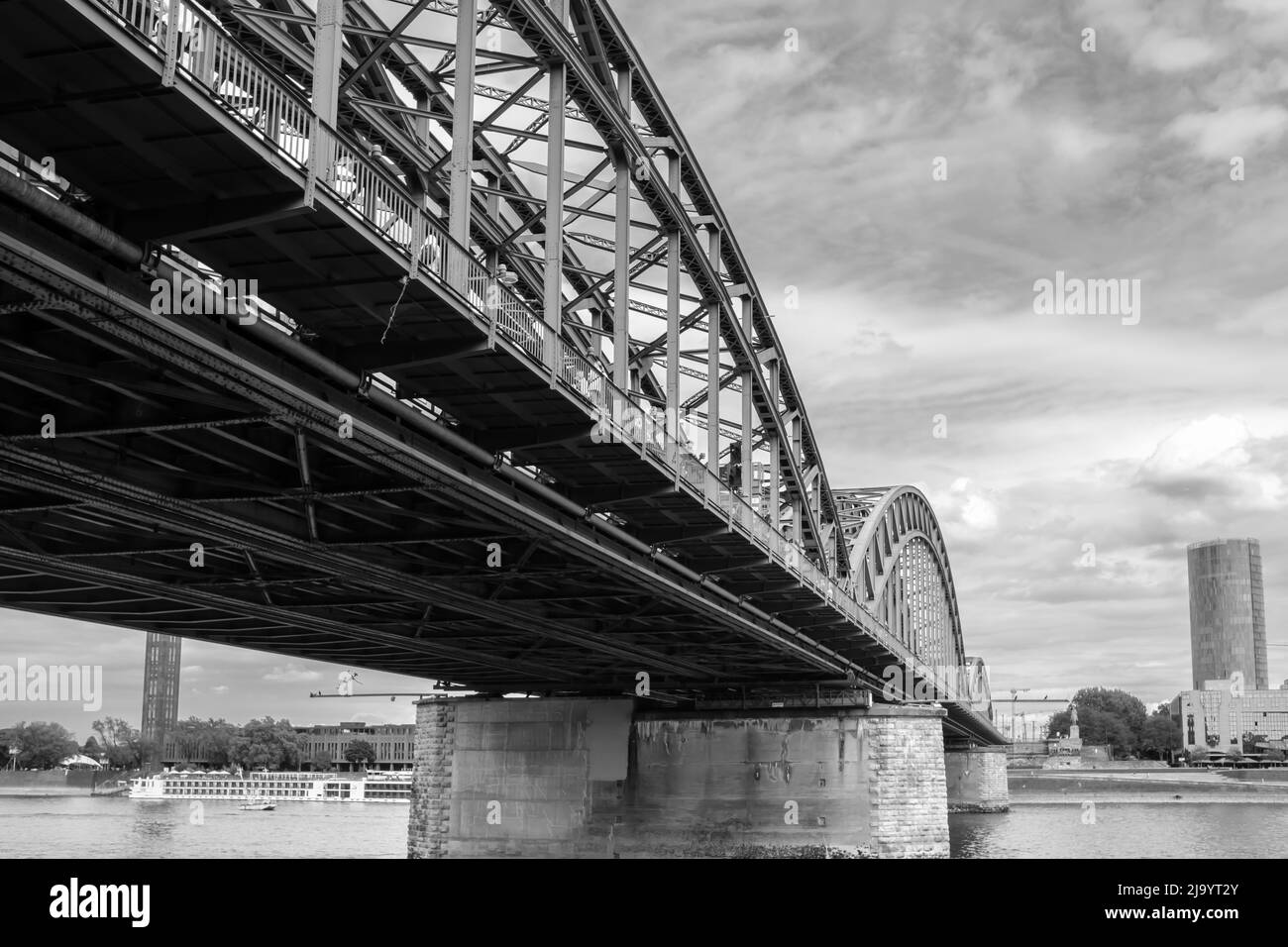 The famous Hohenzollern bridge that is used only by trains and pedestrians and the river Rhine in Cologne in black and white Stock Photo