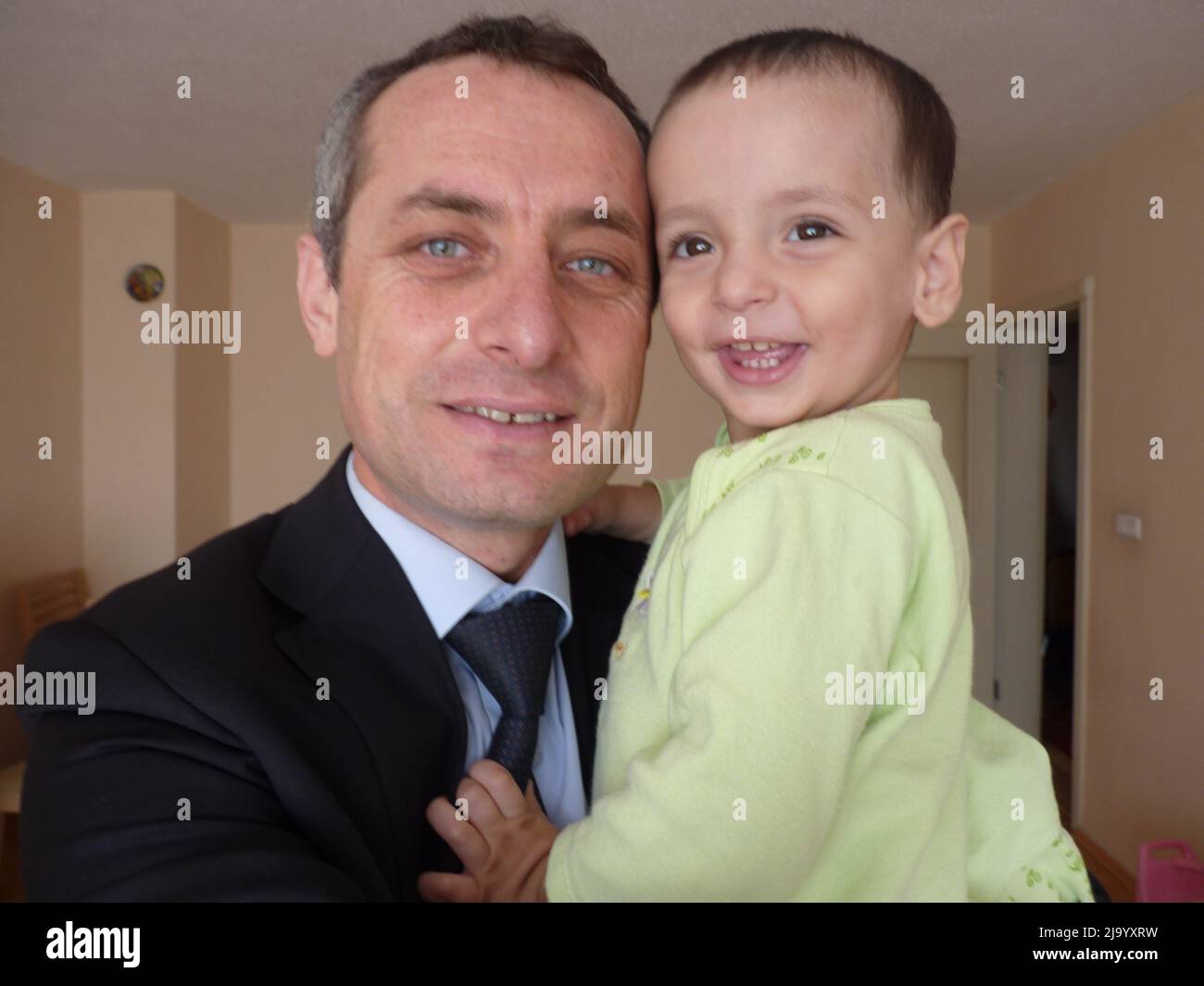 A handsome strong father in white is holding his cute little son in his ...