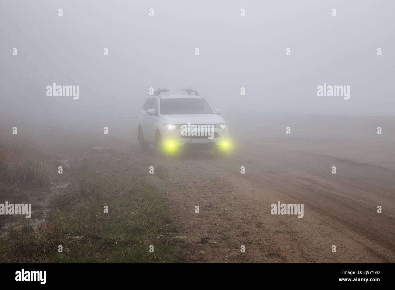 Gum-Bashi pass, North Caucasus, Russia - May 07, 2022: Crossover SUV Mitsubishi Outlander on a mountain road in thick fog with fog lights Stock Photo