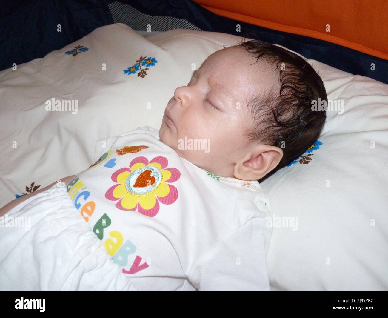 newborn baby sleeps in crib. He has gloves so he doesn't scratch his
