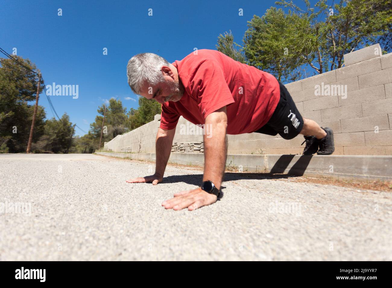Older man with gray hair doing sports in a rural environment, sport improves our health at any age. Stock Photo