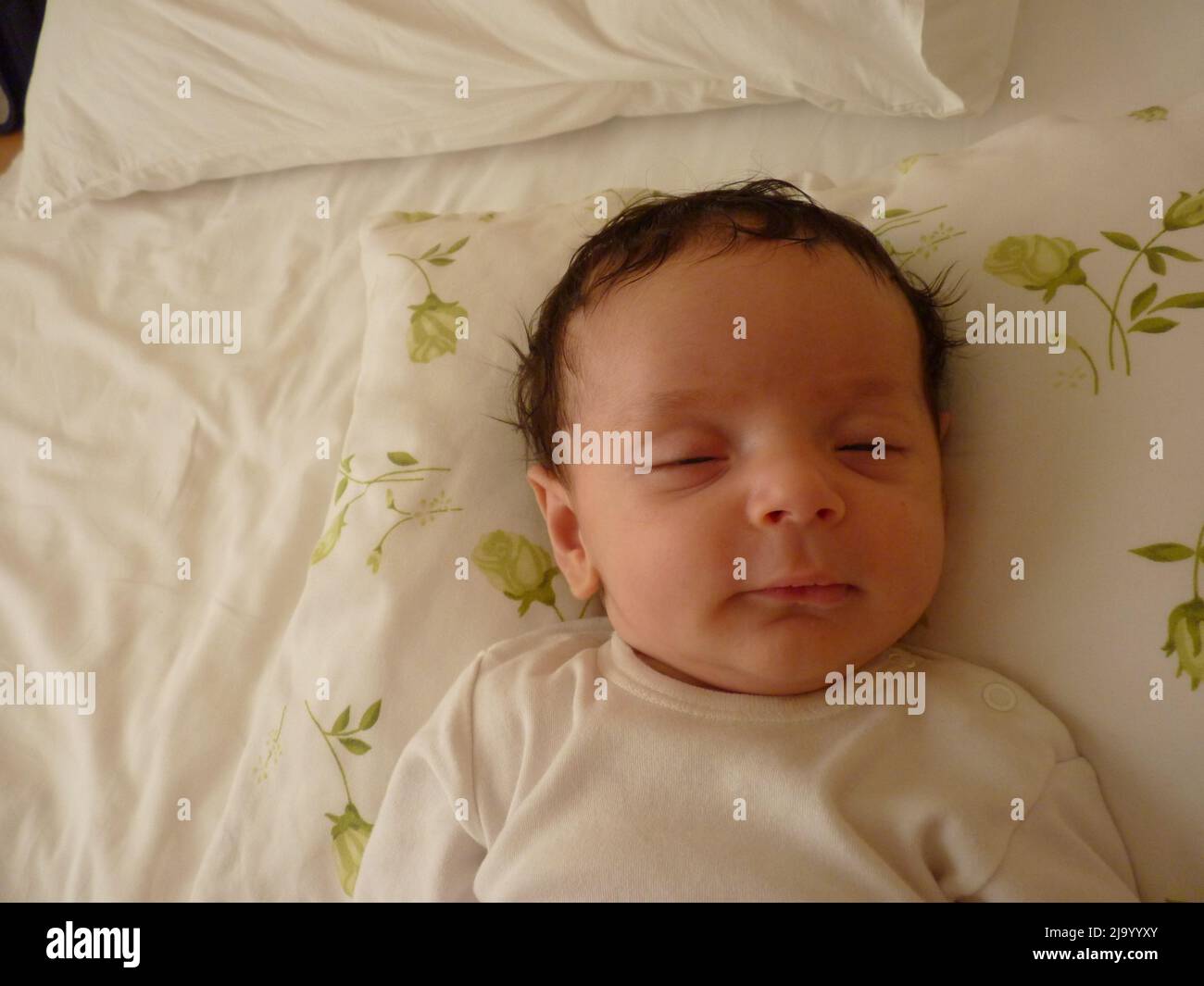 newborn baby sleeps in crib. He has gloves so he doesn't scratch his