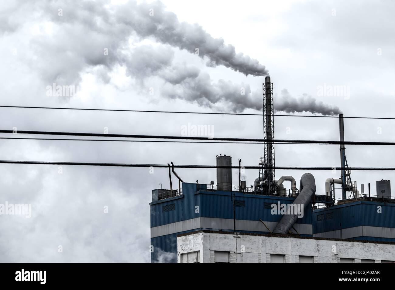Steam coming out of the chimneys of a paper factory facility in Zaragoza, Spain. Air pollution concept Stock Photo