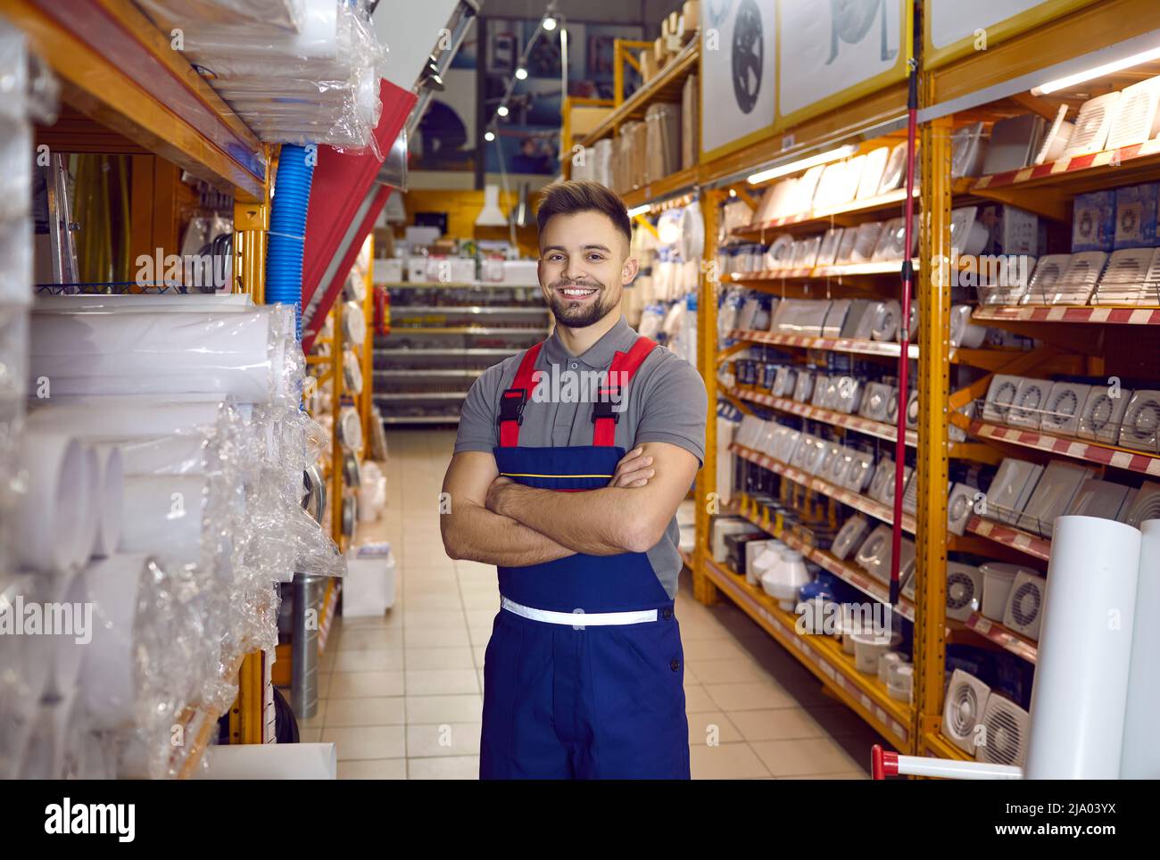 Portrait of happy smiling sales assistant standing in one of aisles at