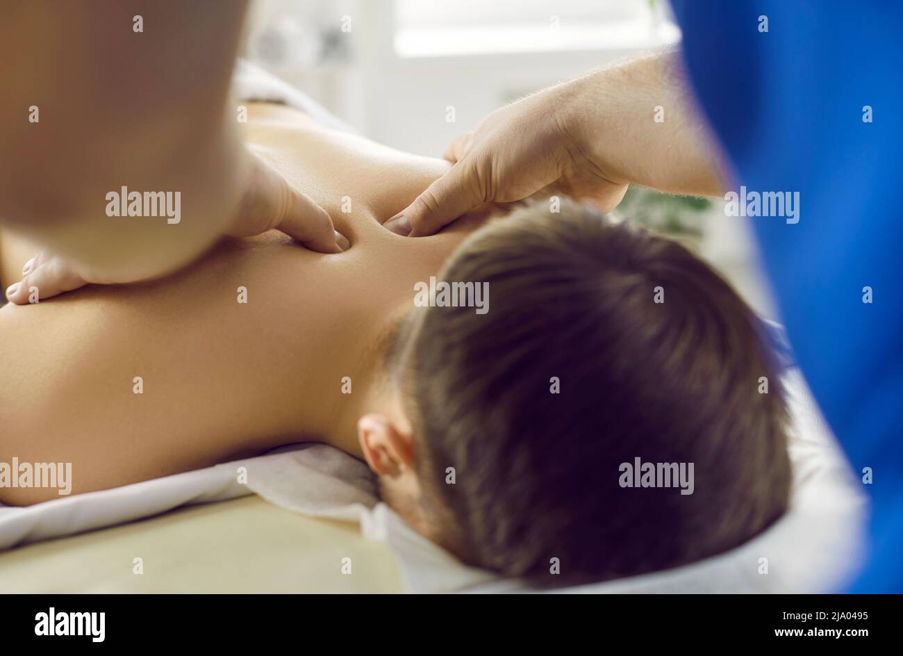 Close up of male masseur hands doing acupuncture healthy osteopathic body massage to young man. Stock Photo