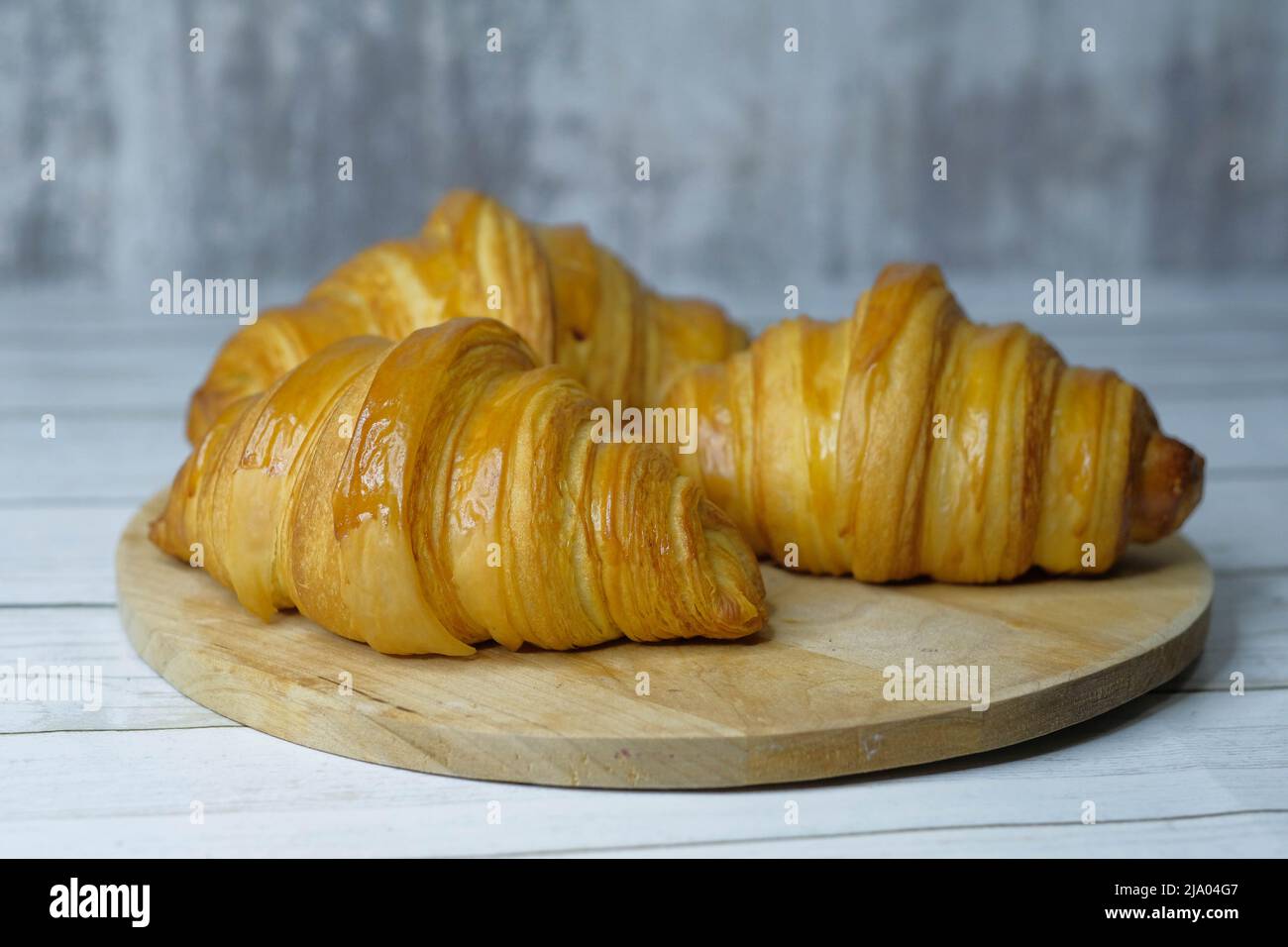 Some fresh croissants on a wooden surface Stock Photo