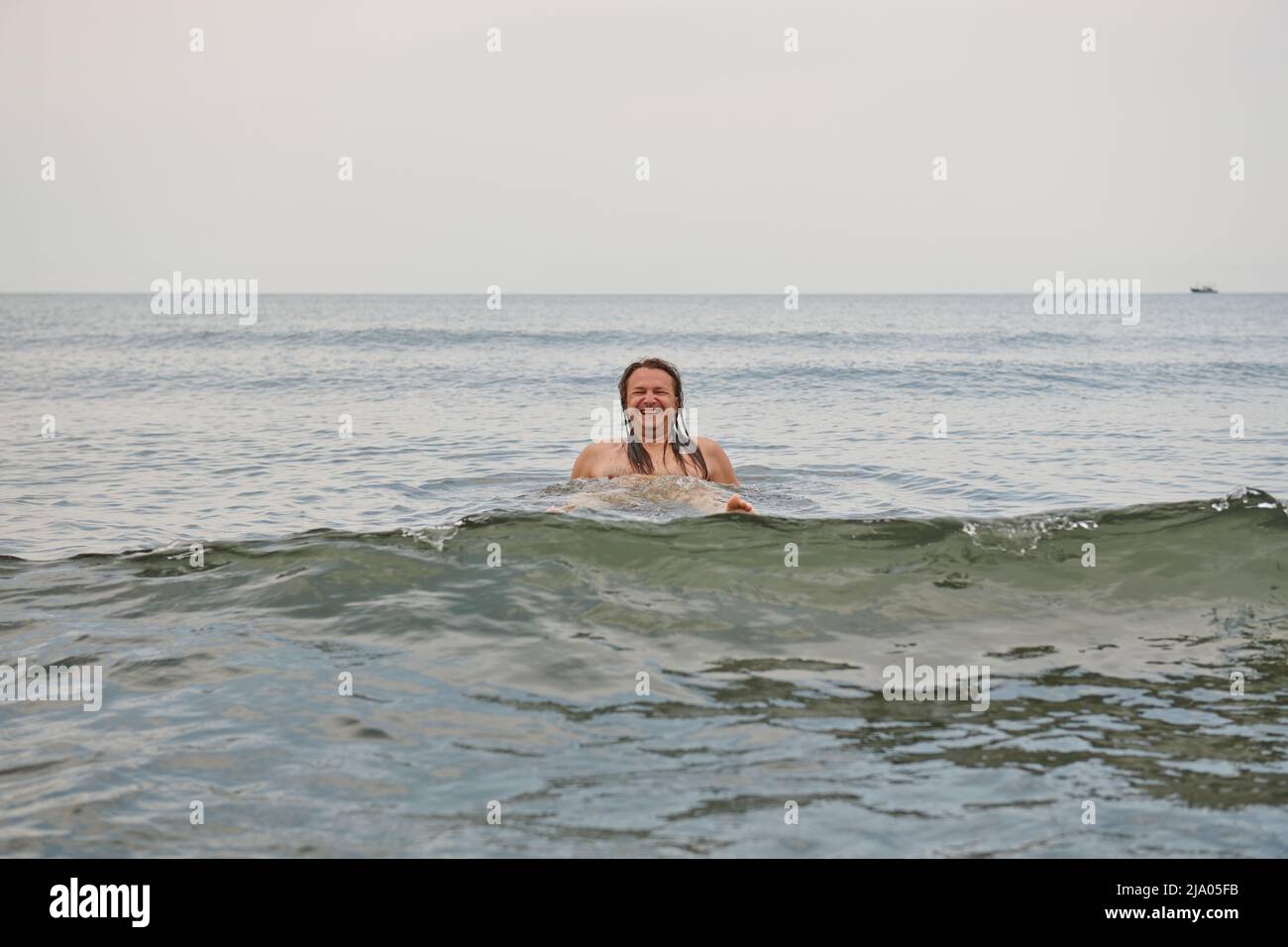 a man with long hair bathes in the sea Stock Photo