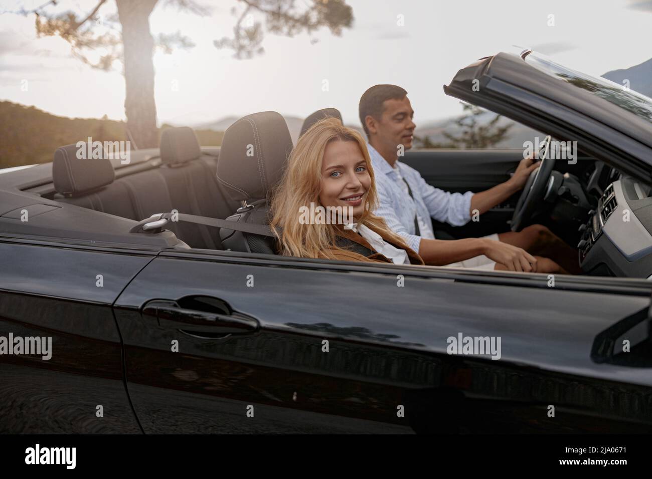 Close up of joyful young female smiling sitting in car with handsome man driving Stock Photo