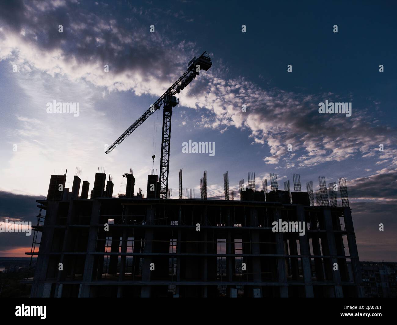 Tower crane and building construction site silhouette at sunrise. The