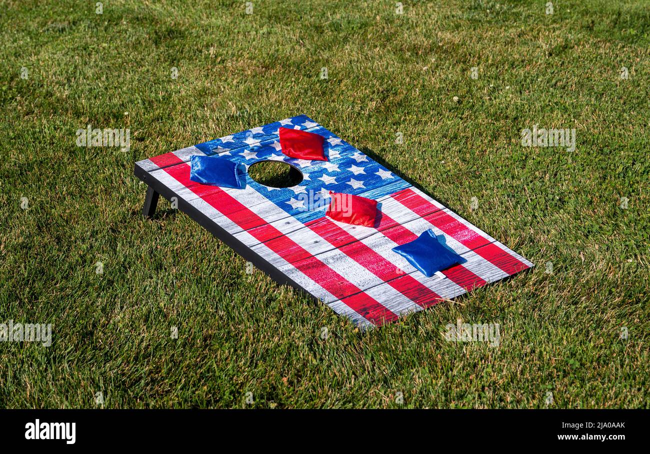 An American Flag corn hole game board on grass with red and blue bean