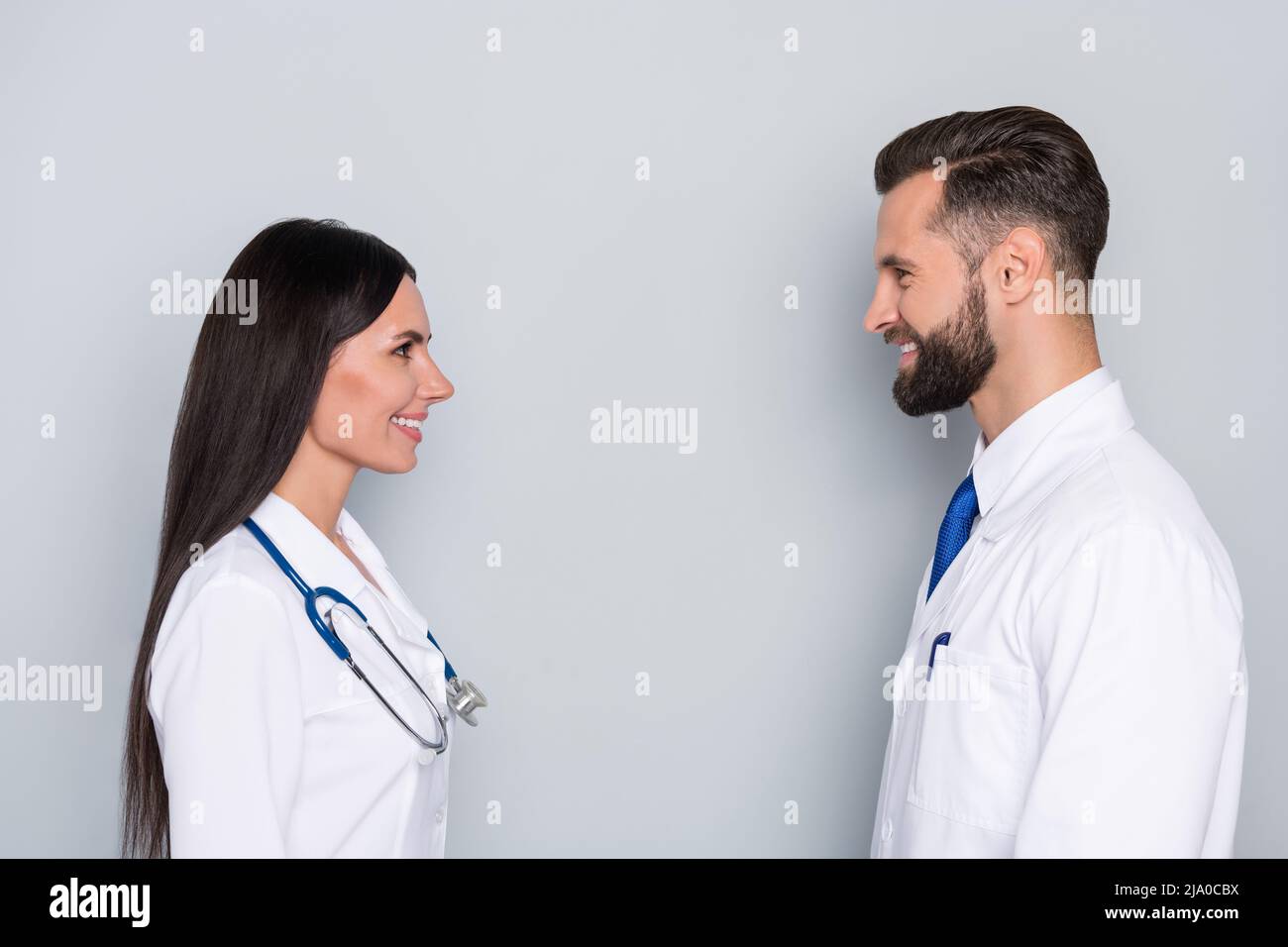Photo of confident positive two doctors wear white coats looking each