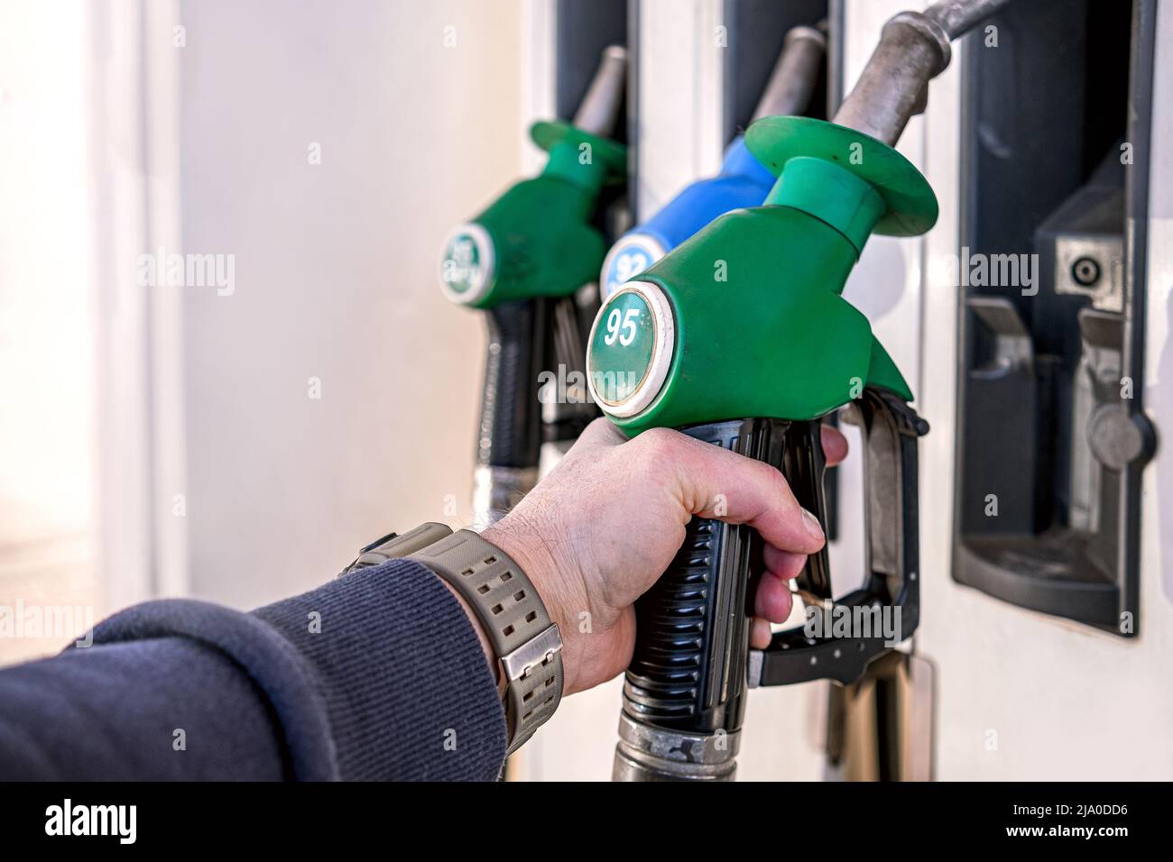A man is about to start filling up a car with gasoline at a gas station. Stock Photo