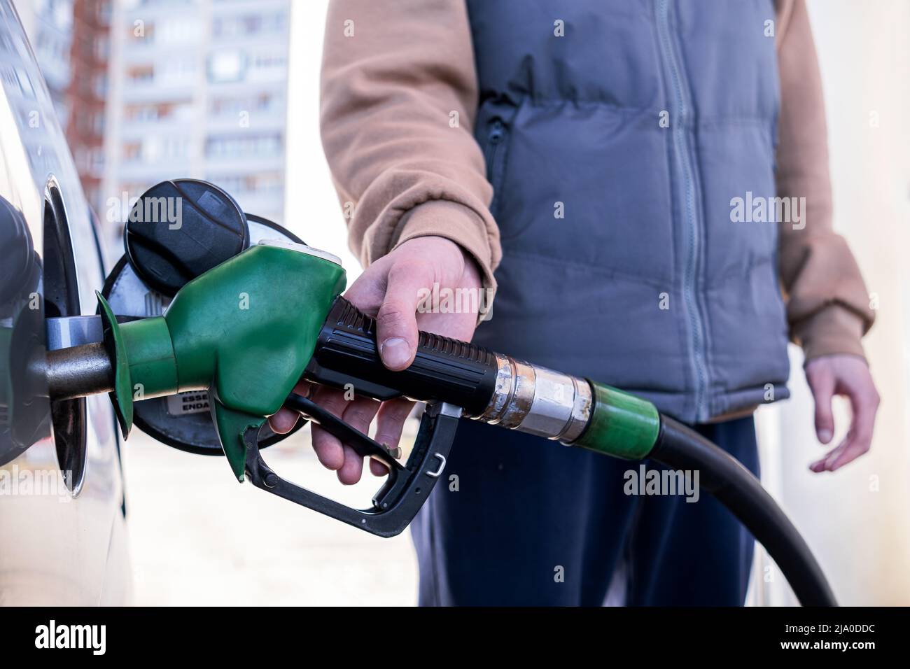 Pumping gasoline fuel into a car at a gas station. The man inserted a fuel pistol into the tank Stock Photo