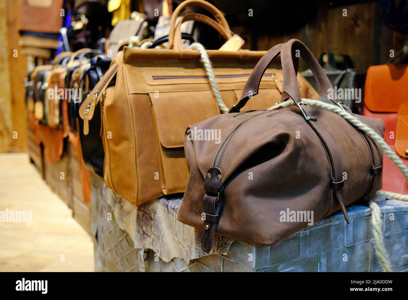 Men's accessories with brown leather bags on wooden table over wall background. Stock Photo