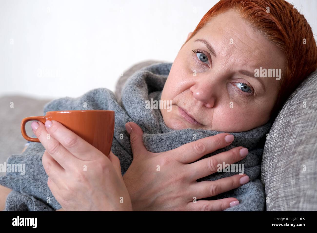 Cold and flu. Woman blowing her nose with a tissue. Stock Photo
