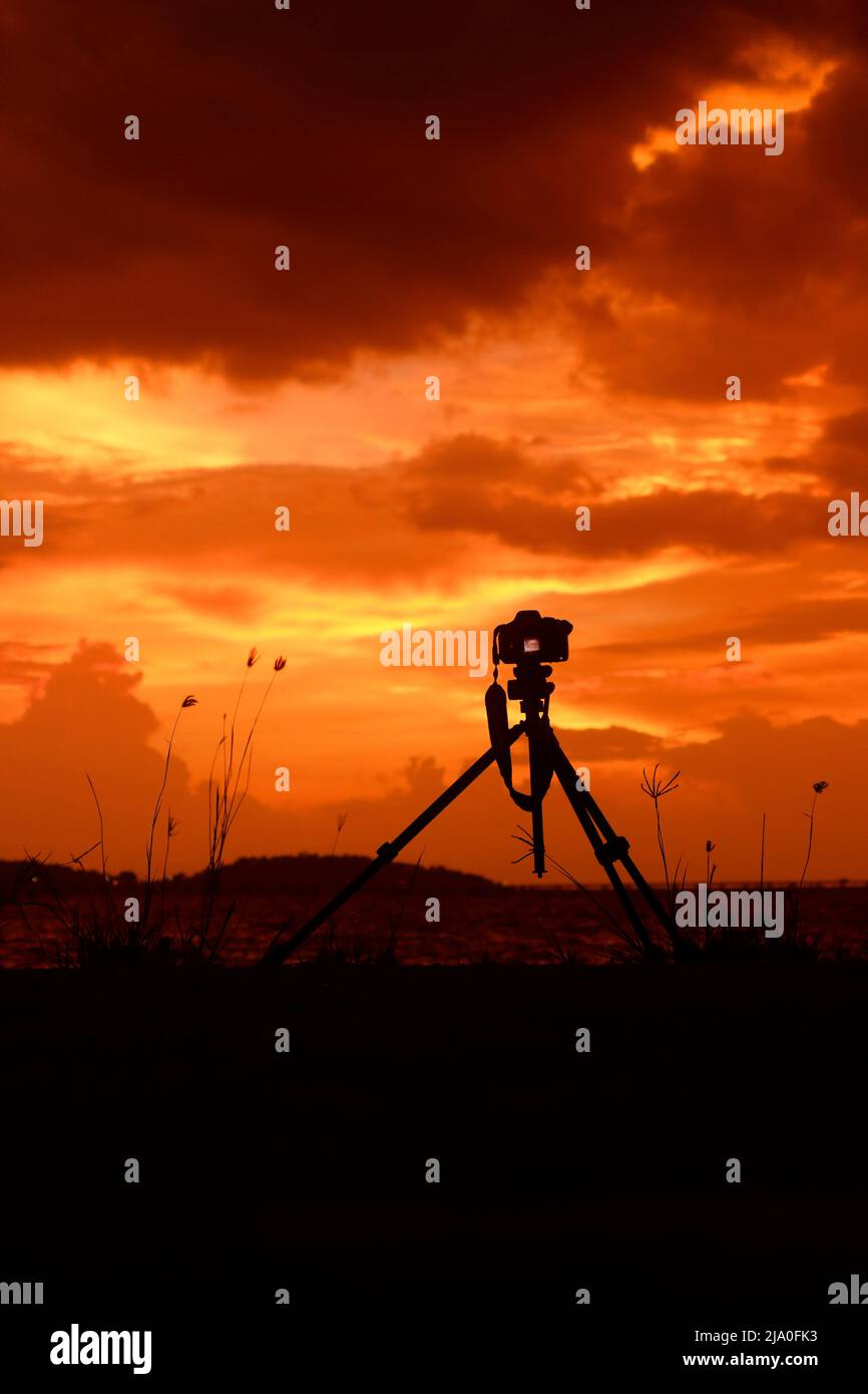 photo camera with tripod At sunset, dusk, colors and shapes of clouds ...