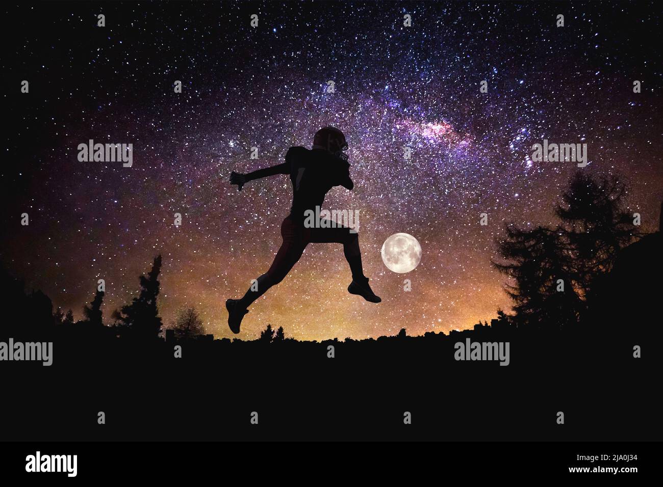 player football man jumping at the night starry sky background. Mixed media Stock Photo
