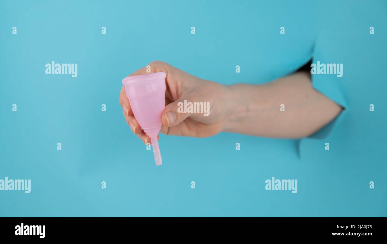 A female hand sticking out of a hole from a blue background holds a