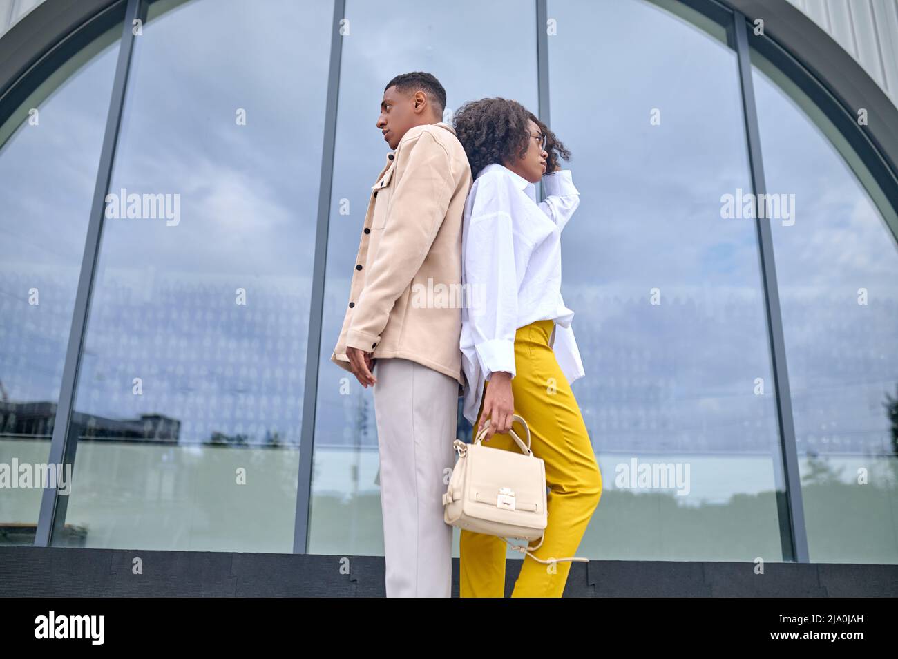 Girl and boy standing with backs to each other Stock Photo - Alamy