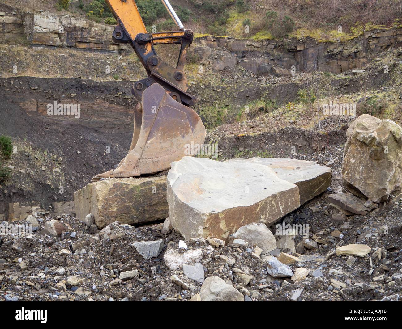 Digger bucket laid to rest upon a giant rock Stock Photo Alamy