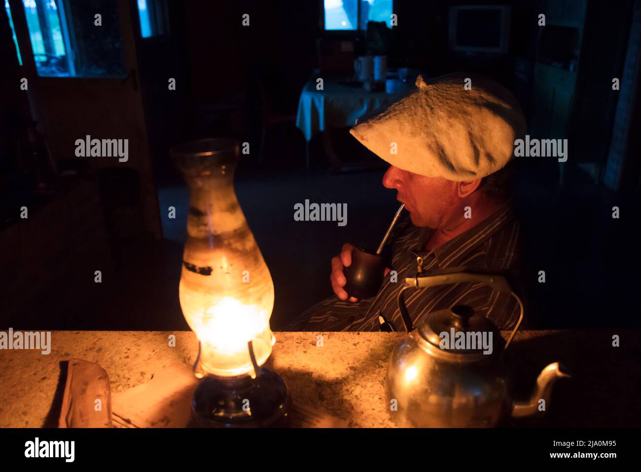 A gaucho drinking mate (National Argentine drink) by the light of a lantern at the Estancia Santa Catalina, Pardo, Buenos Aires province, Argentina. Stock Photo