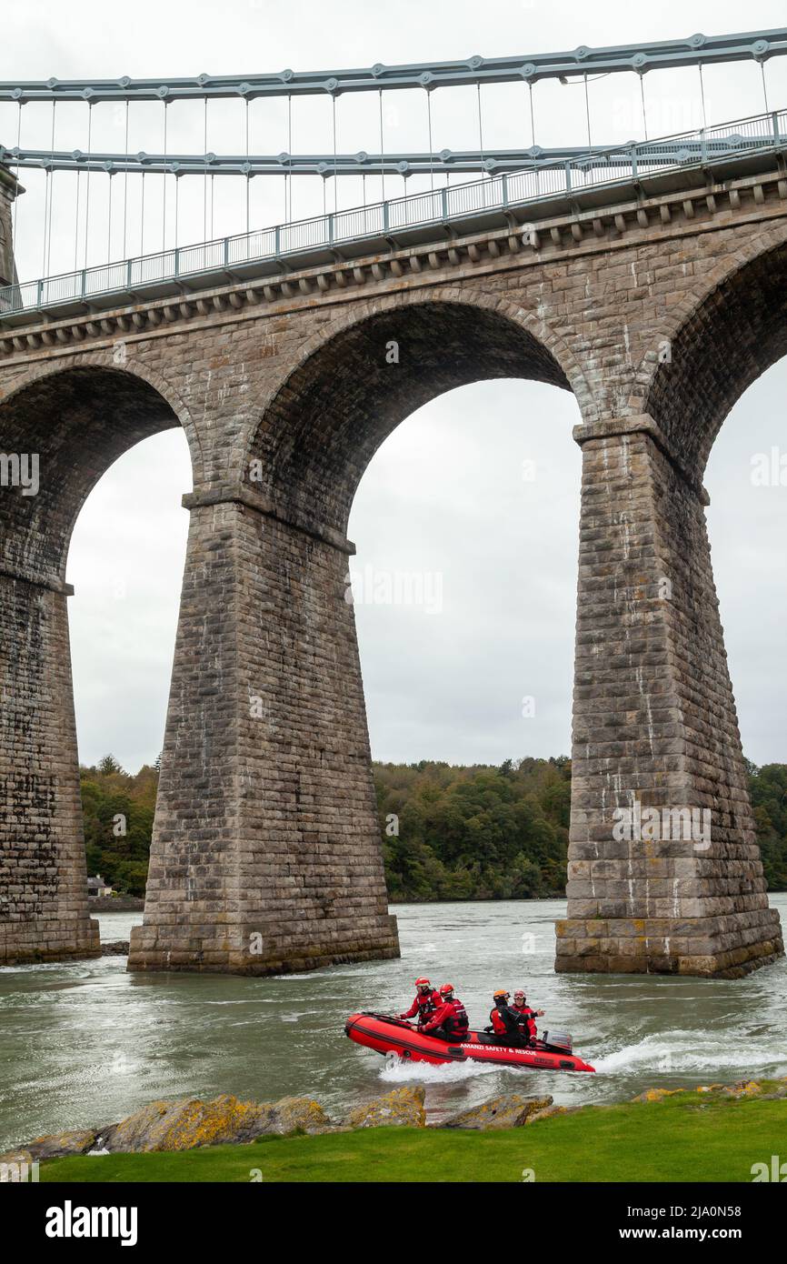An RNLI crew training under the Menai Bridge in an Inflatable lifeboat. Stock Photo