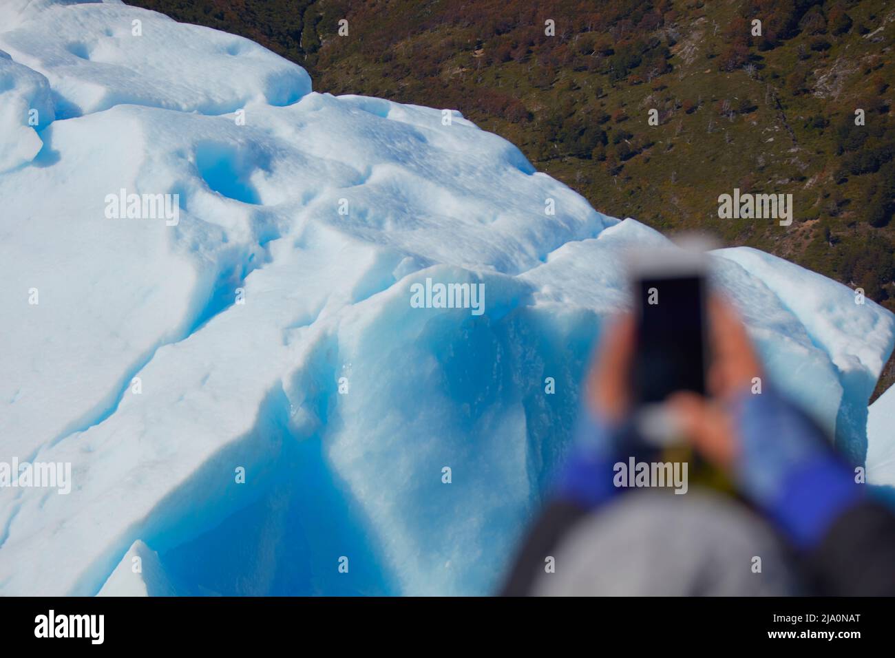 A tourist taking pictures of the Perito Moreno Glacier with a smartphone, Los Glaciares National Park, Argentina. Stock Photo