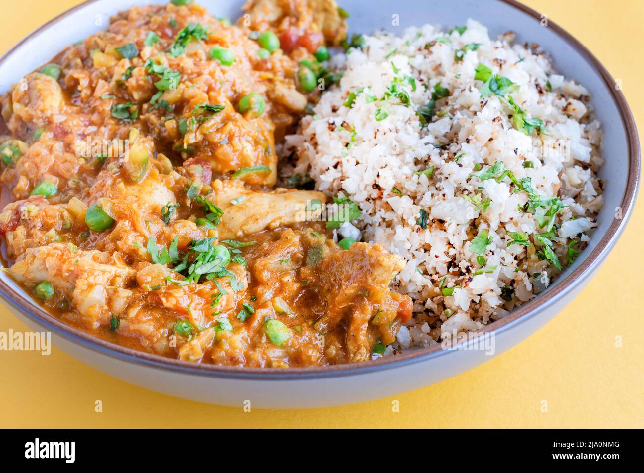 A home made chicken courgette tikka masala curry served in a bowl with cauliflower rice. A healthy protein rich meal choice which is keto friendly Stock Photo