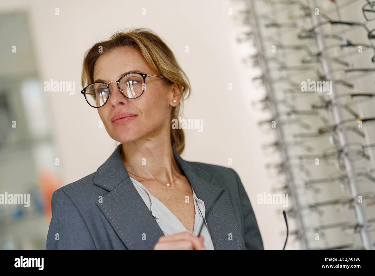 Woman in optic store choosing a new eyeglasses frame. Medical, health