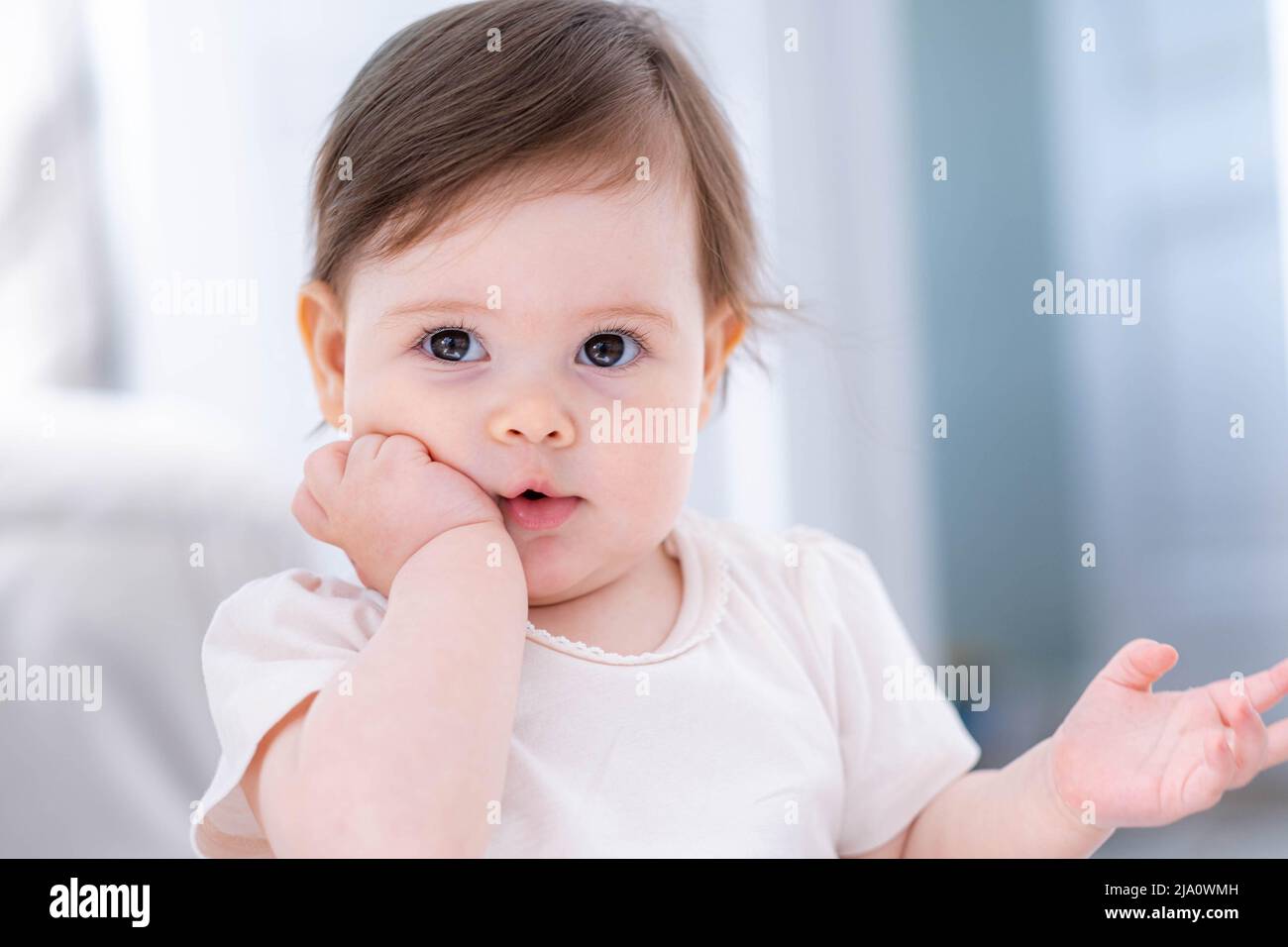 Thoughtful cute little baby girl thinking puzzled of something dreaming or having a good idea, smiling and looking up, imagination. Stock Photo