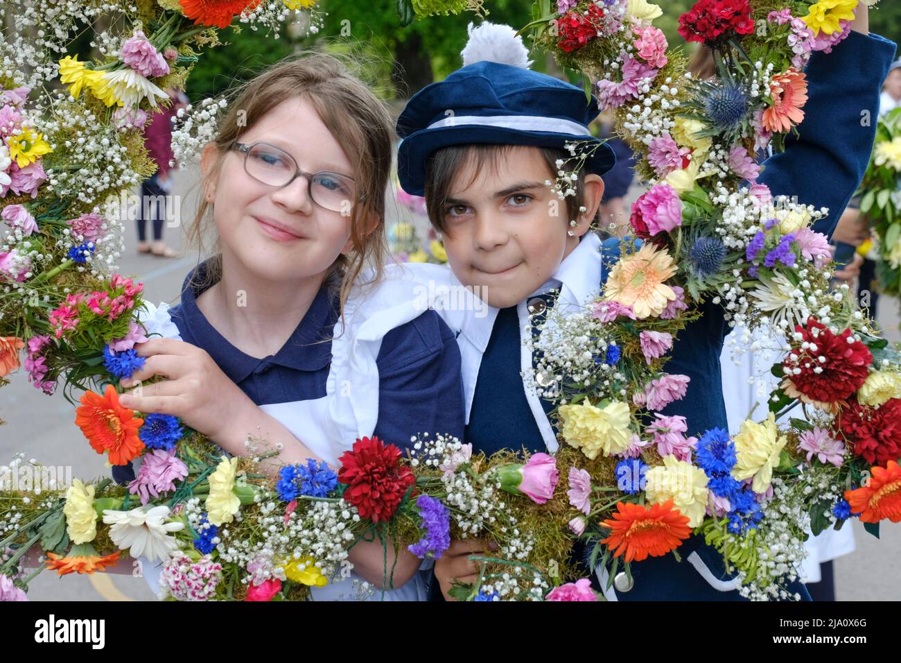 Bisley, Glos, UK. 26th May, 2022. Children from the Blue Coat school dressed in antique costumes are led through the village in a colourful procession. The tradition of dressing the wells in flowers was started in 1863 by the Vicar the Reverend Keble. The procession from the Church of England school takes place on Ascension Day each year. Credit: JMF News/Alamy Live News Stock Photo