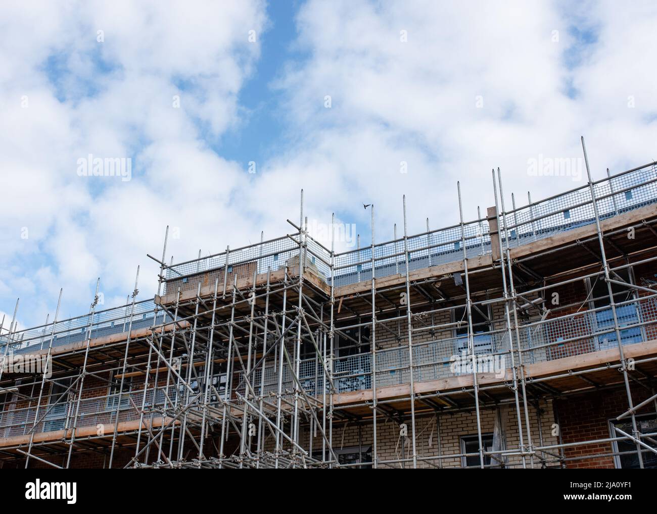 New residential multistorey appartment building made of brick and concrete block, with scaffolds erected around it to provide access for external work Stock Photo