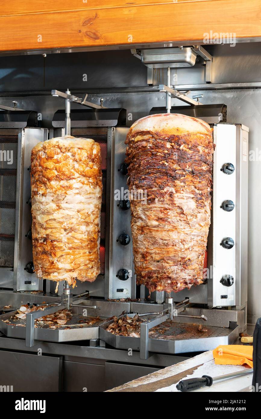 Two rotisseries in a Grecian kebab house cooking lamb and chicken meat  . The meat will be used in kebabs or Greek gyros or souvlaki from the premises. Stock Photo