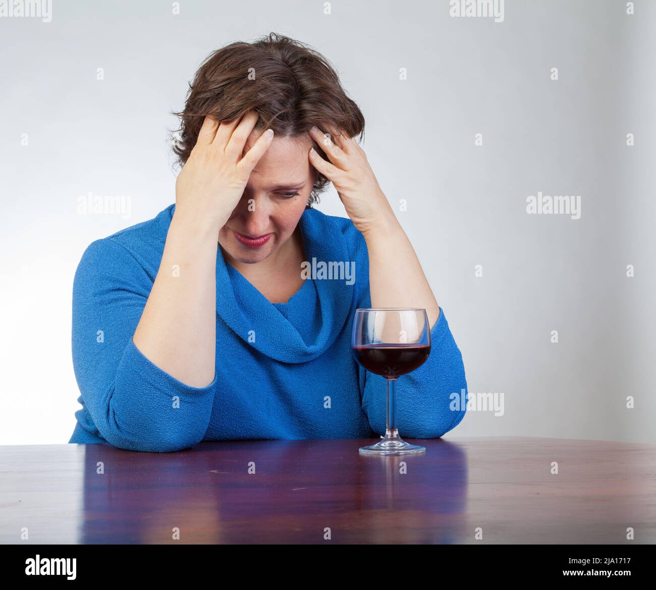 40 something woman staring at a glass of wine looking very upset Stock ...