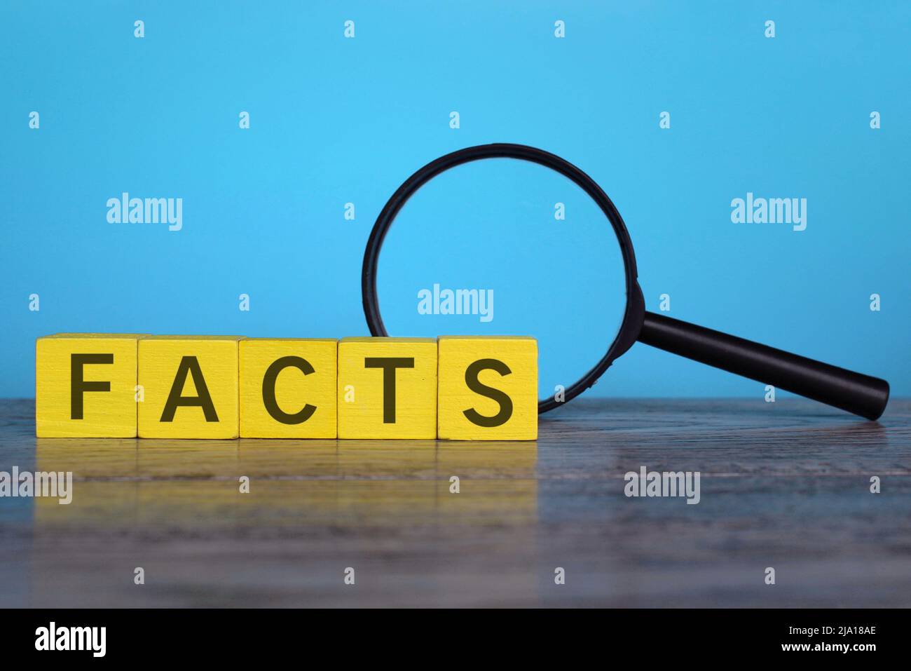 Magnifying glass and wooden cubes with text FACTS. Checking facts and data concept Stock Photo