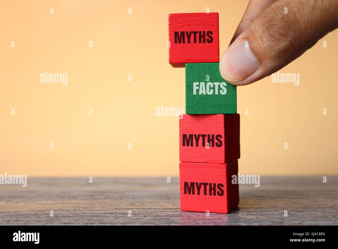 Hand pick wooden cube with text FACTS over MYTHS. Facts vs myths concept. Stock Photo