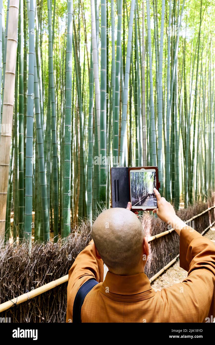 Japan. Kyoto. Arashiyama Bamboo Grove. A buddhist monk taking pictures with his tablet Stock Photo