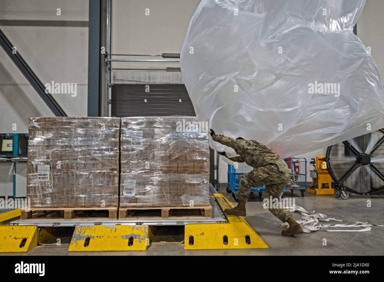 May 23, 2022 - Ramstein Air Base, Germany - U.S. Air Force Airman 1st Class Sukvinder Riar-Sotelo, 72st Aerial Port Squadron cargo processing specialist, throws a plastic bag over a pallet of infant formula at Ramstein Air Base. Riar-Sotelo and others helped process, package and load 132 pallets of medical grade infant formula onto a U.S. Air Force C-17 Globemaster III aircraft for rapid transport to the United States for further distribution. A second shipment of formula began arriving May 23 at Ramstein Air Base for processing and loading onto a commercial contracted carrier destined for the Stock Photo
