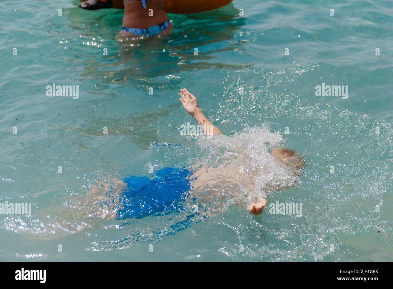 Child learning to swim in the open sea of tropical resort. Kids learn swimming. Exercise and